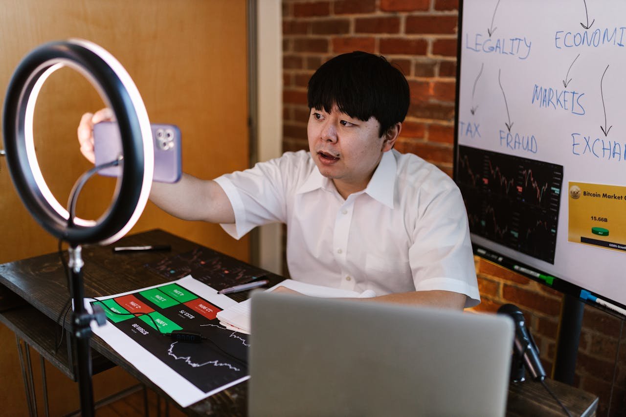 our-services-3 Young man filming a vlogger video about cryptocurrency trading with charts and graphs.